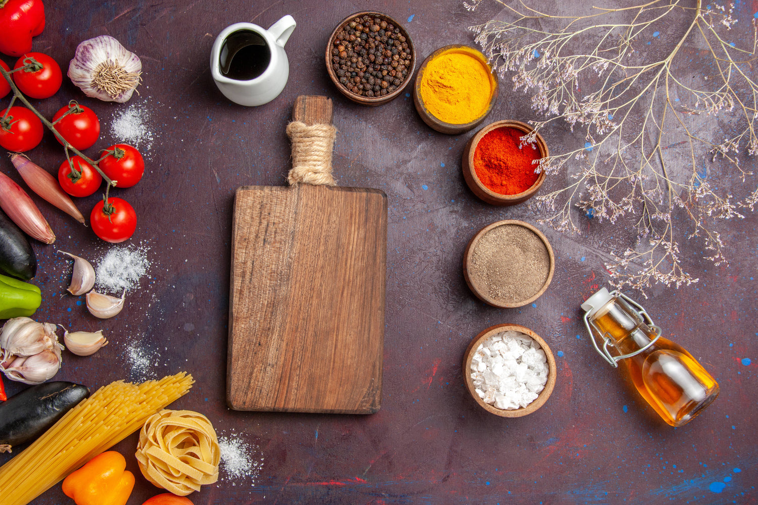 Top-view layout of fresh cooking ingredients, spices, pasta, and oil around a rustic wooden cutting board for AeroCook home page banner.